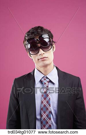 Stock Photo - A man wearing many sunglasses on his eyes. Fotosearch