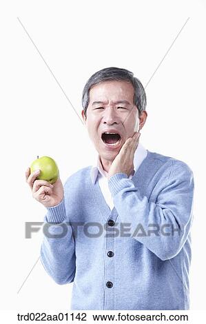 A painful elderly man with toothache while holding an apple View Large Photo Image Stock Image - A painful elderly man with toothache while holding an apple . Fotosearch