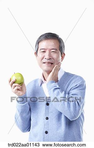A painful elderly man with toothache while holding an apple  View Large Photo Image Stock Image - A painful elderly man with toothache while holding an apple . Fotosearch