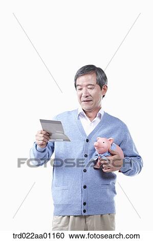 A smiling elderly man looking at the bankbook with a piggy bank View Large Photo Image Stock Image - A smiling elderly man looking at the bankbook with a piggy bank. Fotosearch