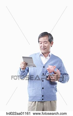 A smiling elderly man looking at the bankbook with a piggy bank View Large Photo Image Stock Image - A smiling elderly man looking at the bankbook with a piggy bank. Fotosearch