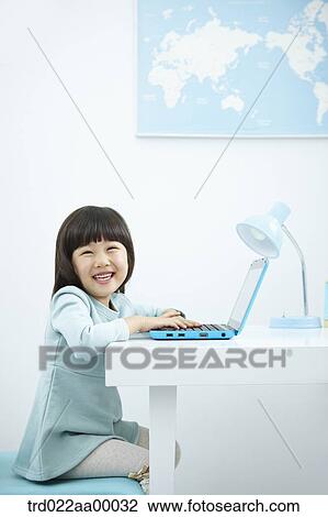 A smiling girl having her hands on keyboard of a laptop in front of the desk View Large Photo Image Stock Image - A smiling girl having her hands on keyboard of a laptop in front of the desk. Fotosearch