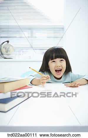 Stock Image - A smiling girl holding a notebook and pencil . Fotosearch