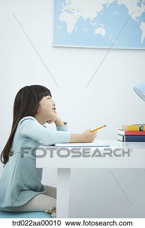 A smiling girl holding a pencil over a book View Large Photo Image Stock Image - A smiling girl holding a pencil over a book. Fotosearch