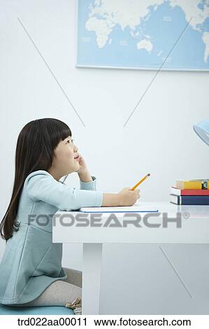 A smiling girl holding a pencil over a book View Large Photo Image Stock Image - A smiling girl holding a pencil over a book. Fotosearch