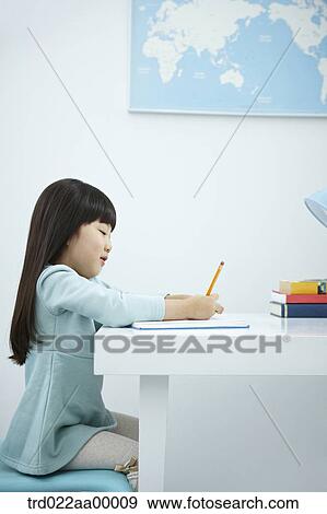 A smiling girl holding a pencil over a book View Large Photo Image Stock Photo - A smiling girl holding a pencil over a book. Fotosearch