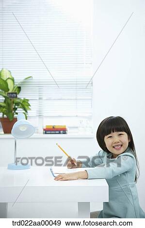 A smiling girl holding a pencil over a book View Large Photo Image Stock Photo - A smiling girl holding a pencil over a book. Fotosearch