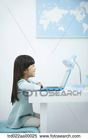 A smiling girl looking at a laptop in front of the desk View Large Photo Image Stock Photography - A smiling girl looking at a laptop in front of the desk. Fotosearch