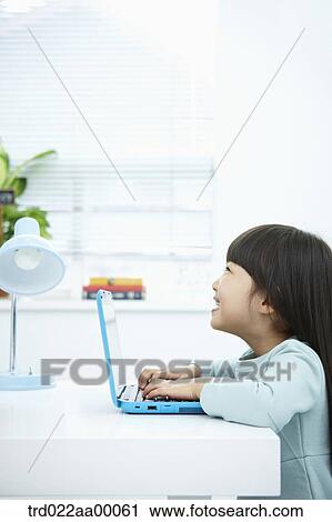 A smiling girl pushing the keyboard of a laptop in front of the desk View Large Photo Image Stock Image - A smiling girl pushing the keyboard of a laptop in front of the desk. Fotosearch