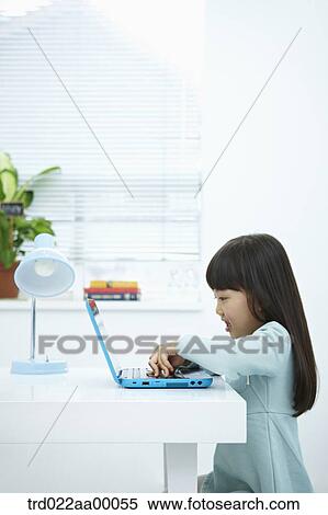 A smiling girl pushing the keyboard of a laptop in front of the desk View Large Photo Image Stock Photography - A smiling girl pushing the keyboard of a laptop in front of the desk. Fotosearch