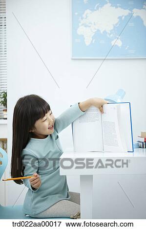 A smiling girl showing a book in front of the desk View Large Photo Image Stock Photo - A smiling girl showing a book in front of the desk. Fotosearch