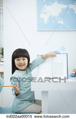 A smiling girl showing a book in front of the desk View Large Photo Image Stock Photography - A smiling girl showing a book in front of the desk. Fotosearch