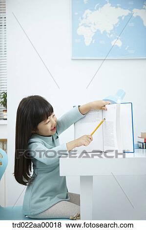 A smiling girl showing a book with a pencil View Large Photo Image Stock Photo - A smiling girl showing a book with a pencil . Fotosearch