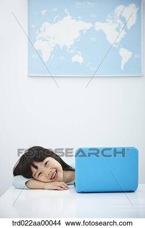 A smiling girl with a laptop on the desk View Large Photo Image Picture - A smiling girl with a laptop on the desk. Fotosearch
