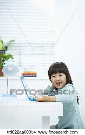 A smiling girl with a laptop on the desk View Large Photo Image Picture - A smiling girl with a laptop on the desk. Fotosearch
