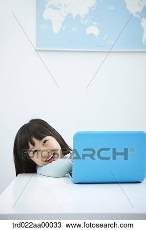 A smiling girl with a laptop on the desk View Large Photo Image Stock Image - A smiling girl with a laptop on the desk. Fotosearch