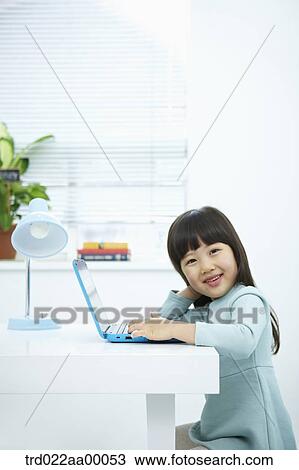 A smiling girl with a laptop on the desk View Large Photo Image Stock Image - A smiling girl with a laptop on the desk. Fotosearch