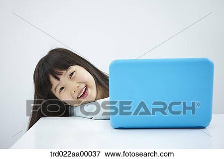 A smiling girl with a laptop on the desk View Large Photo Image Stock Photo - A smiling girl with a laptop on the desk. Fotosearch