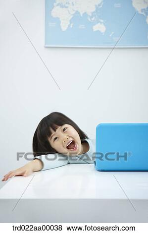 Stock Photo - A smiling girl with a laptop on the desk. Fotosearch