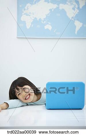 A smiling girl with a laptop on the desk View Large Photo Image Stock Photo - A smiling girl with a laptop on the desk. Fotosearch