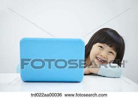 A smiling girl with a laptop on the desk View Large Photo Image Stock Photograph - A smiling girl with a laptop on the desk. Fotosearch