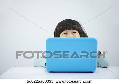 Stock Photography - A smiling girl with a laptop on the desk. Fotosearch
