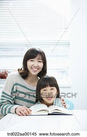A smiling woman and girl with a book on the desk View Large Photo Image Stock Photography - A smiling woman and girl with a book on the desk. Fotosearch