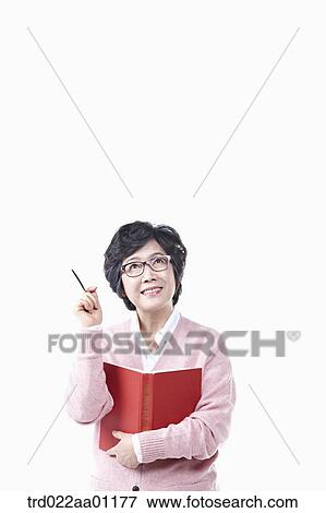 Stock Photo - A thinking elderly woman with a book and pen. Fotosearch