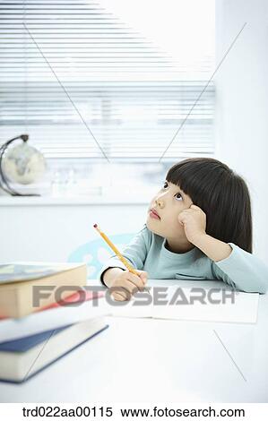 Stock Photography - A thinking girl while holding a pencil over a note book. Fotosearch