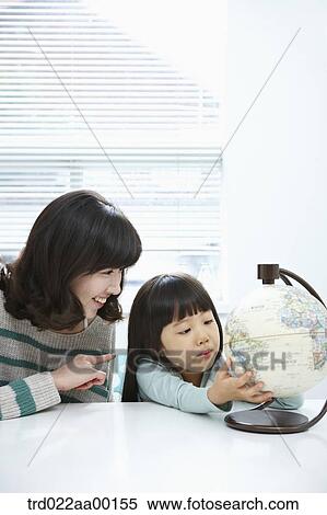 Stock Photography - A woman and girl looking at a globe. Fotosearch