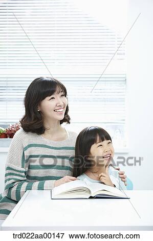 A woman and girl looking at the right side with a book on the desk View Large Photo Image Stock Photo - A woman and girl looking at the right side with a book on the desk. Fotosearch