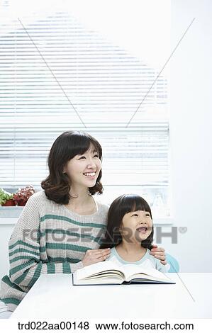 A woman and girl looking at the right side with a book on the desk View Large Photo Image Stock Photo - A woman and girl looking at the right side with a book on the desk. Fotosearch