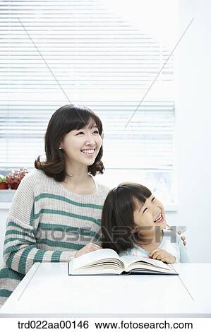 A woman and girl looking at the right side with a book on the desk View Large Photo Image Stock Photograph - A woman and girl looking at the right side with a book on the desk. Fotosearch