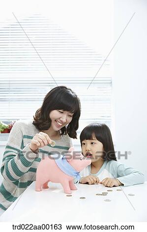 A woman and girl putting a coin into a pink piggy bank View Large Photo Image Stock Image - A woman and girl putting a coin into a pink piggy bank. Fotosearch