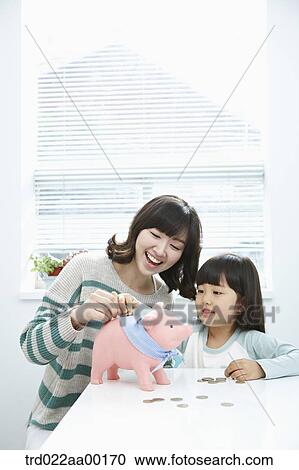 A woman and girl putting a coin into a pink piggy bank View Large Photo Image Stock Image - A woman and girl putting a coin into a pink piggy bank. Fotosearch