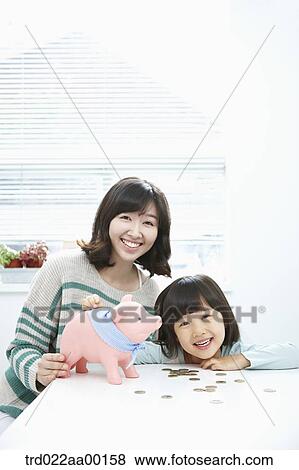 A woman and girl with a pink piggy bank and coin on the desk View Large Photo Image Stock Photo - A woman and girl with a pink piggy bank and coin on the desk. Fotosearch