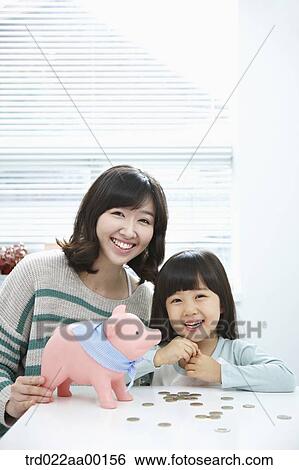 A woman and girl with a pink piggy bank and coin on the desk View Large Photo Image Stock Photograph - A woman and girl with a pink piggy bank and coin on the desk. Fotosearch