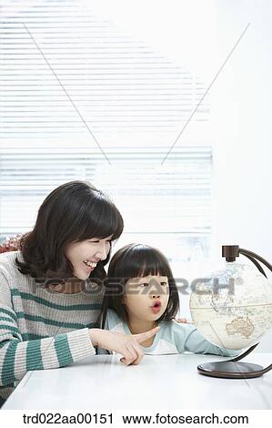 A woman pointing to a globe and girl looking at a globe View Large Photo Image Stock Image - A woman pointing to a globe and girl looking at a globe. Fotosearch