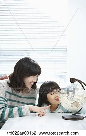 A woman pointing to a globe and girl looking at a globe View Large Photo Image Stock Image - A woman pointing to a globe and girl looking at a globe. Fotosearch