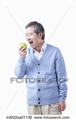 Stock Photograph - An elderly man biting an apple . Fotosearch
