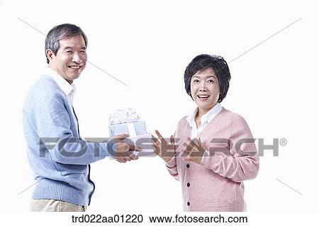 Stock Image - An elderly man giving the gift for an elderly woman . Fotosearch