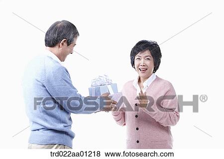 Stock Photo - An elderly man giving the gift for an elderly woman . Fotosearch