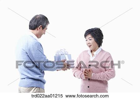 Stock Photography - An elderly man giving the gift for an elderly woman . Fotosearch