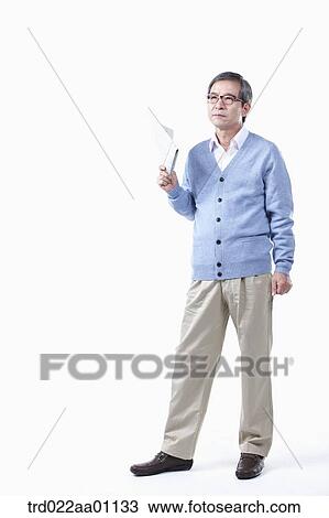 Stock Image - An elderly man holding a newspaper in glasses. Fotosearch