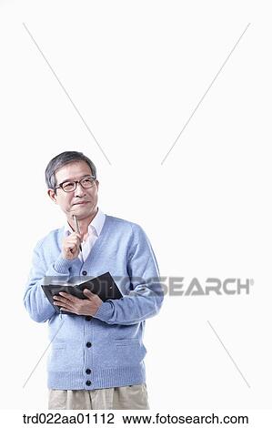 Stock Image - An elderly man holding a pen and planner in glasses. Fotosearch