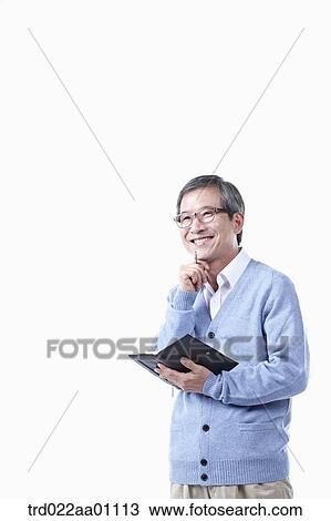 Stock Image - An elderly man holding a pen and planner in glasses. Fotosearch