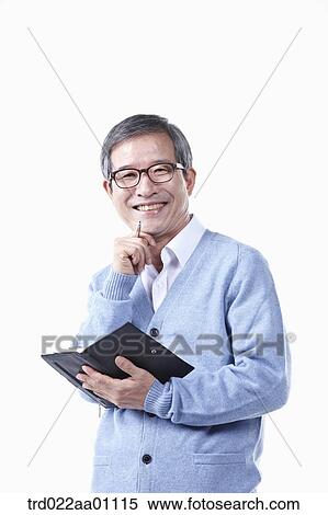 Stock Photography - An elderly man holding a pen and planner in glasses. Fotosearch