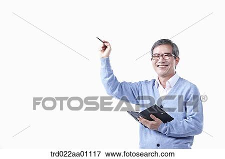 Stock Photo - An elderly man pointing to the air with a pen in glasses. Fotosearch