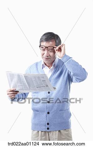 Picture - An elderly man reading a newspaper in glasses. Fotosearch