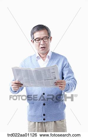 Stock Photograph - An elderly man reading a newspaper in glasses. Fotosearch